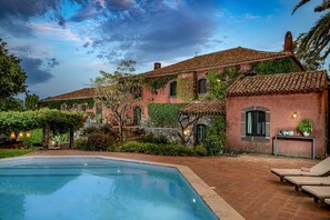 A poolside area with a clear view of a building with a tiled roof and a stone wall.