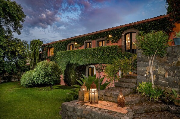 Una casa con jardín, escalones de piedra y faroles.