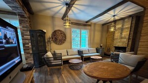 Un salon chaleureux avec un plancher en bois, une grande table ronde, un canapé et un téléviseur.