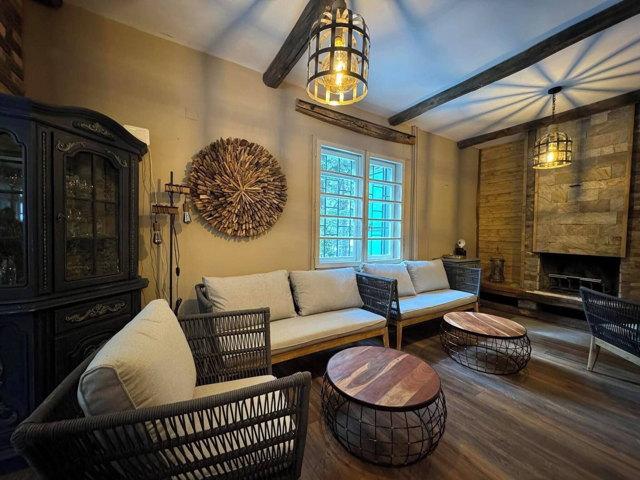 A cozy lounge area with a sofa, wicker chairs, and round wooden tables.