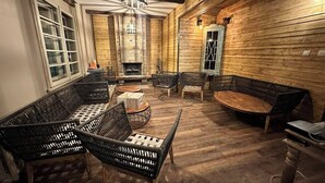 Une pièce chaleureuse, meublée de meubles en osier, avec une cheminée et des murs en bois.