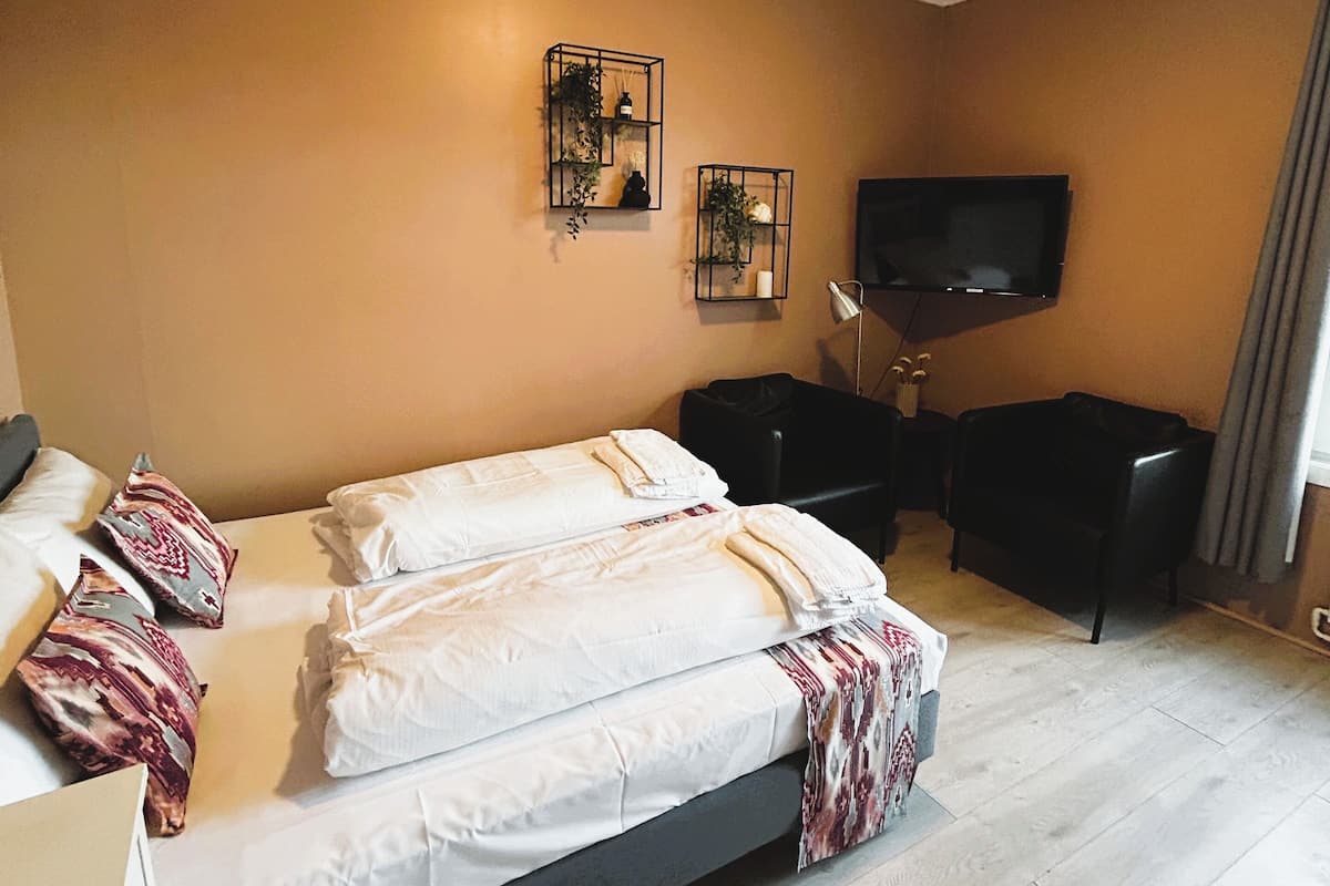 Een hotelkamer met een bed, een bureau, een stoel, een televisie en twee wandplanken met planten.