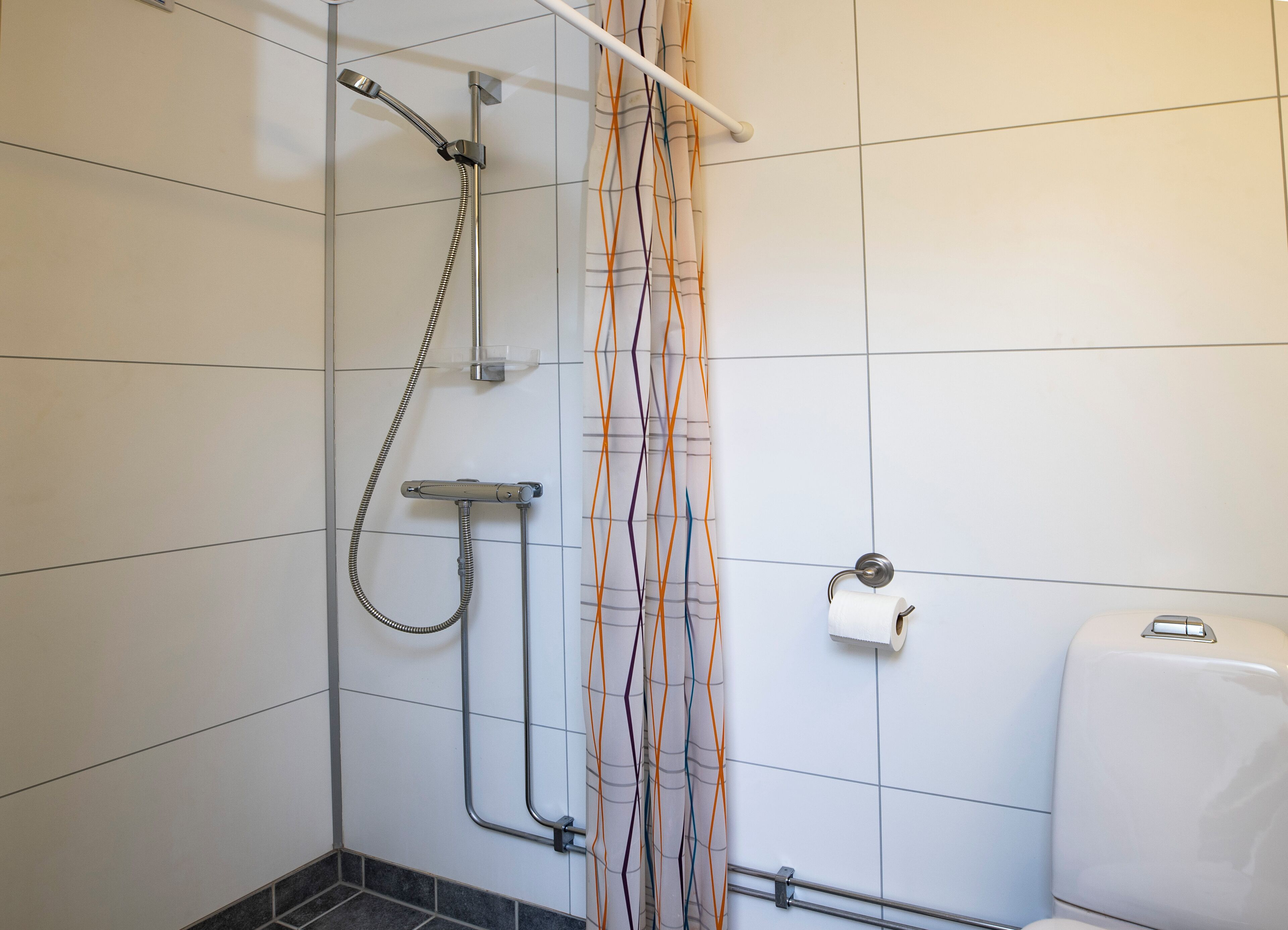 A bathroom with a shower, toilet, and a towel rack.