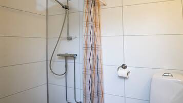 A bathroom with a shower, toilet, and a towel rack.