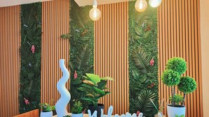 Un mostrador de recepción con un cartel que dice 'Welcome', plantas en macetas y una pared de listones de madera.