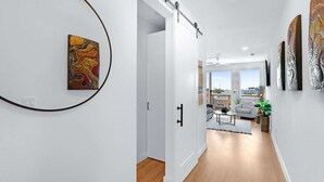 Un couloir avec une porte coulissante donnant sur un salon offrant une vue sur la ville.