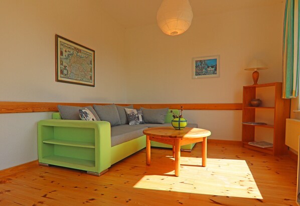 A cozy living room with a green sofa, a wooden coffee table, and a map on the wall.