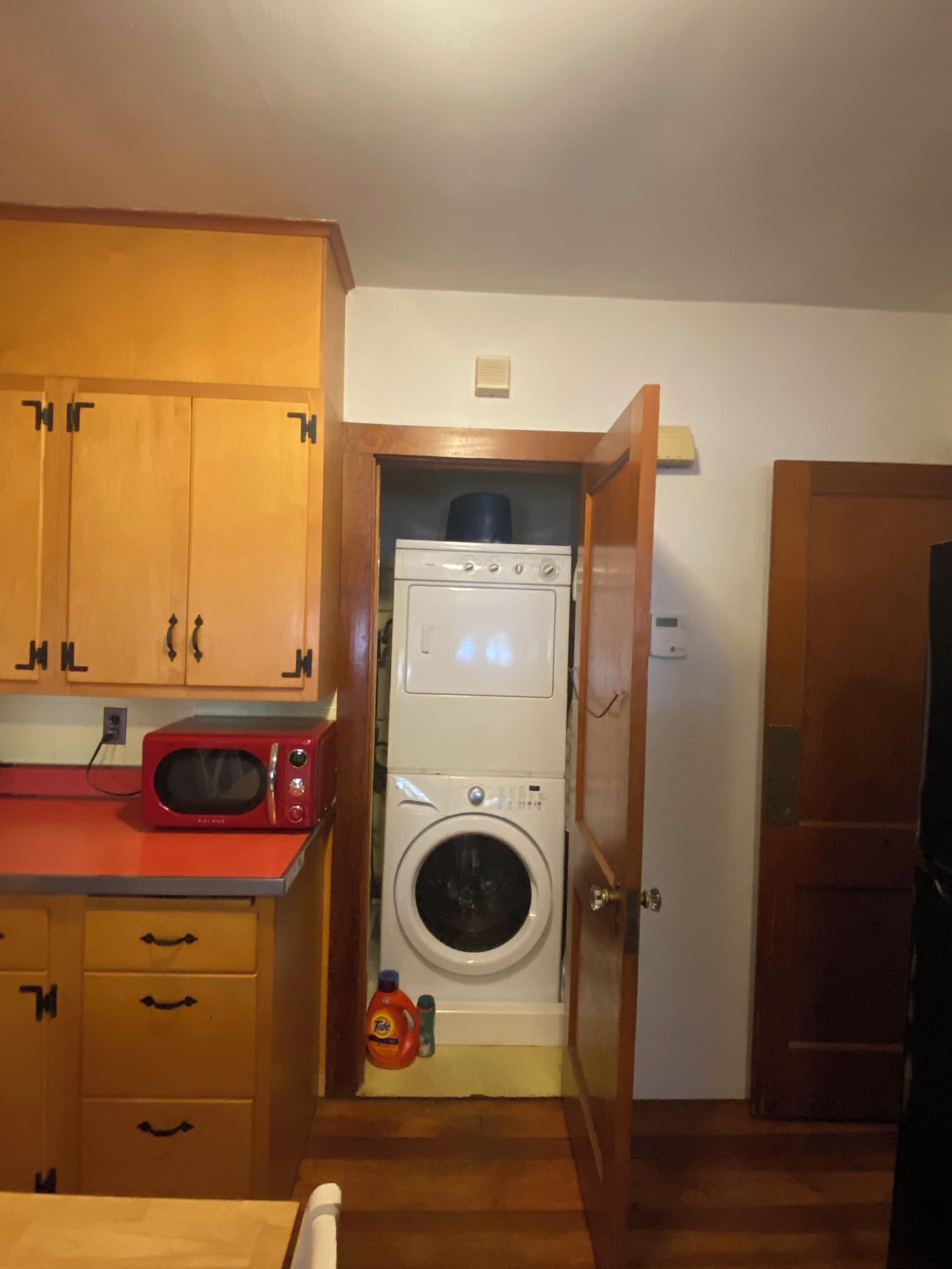 Une cuisine compacte avec des meubles en bois, un four à micro-ondes et un lave-linge.