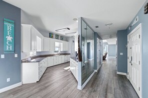 A modern kitchen with white cabinets, a marble countertop, and a wooden floor. - Beautiful, Newly Renovated, Pet Friendly Condo with Stunning Gulf Views! (Pensacola Beach)
