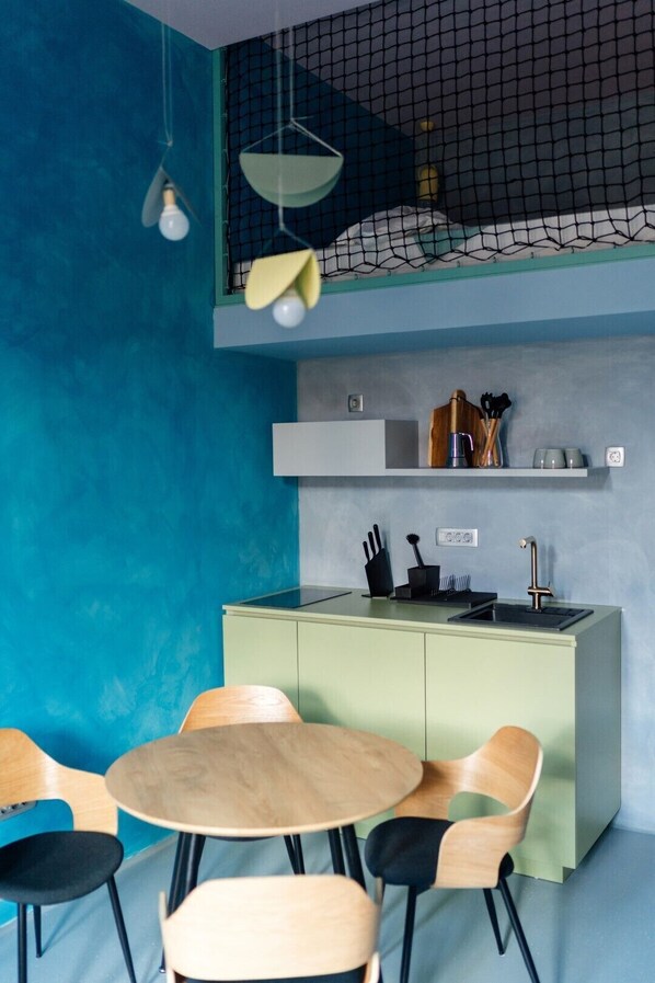 A modern kitchen with a green island, a dining area with wooden chairs, and a blue accent wall. - Tomosmatik Apartments Koper (Koper)