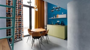 Cozinha moderna com parede azul, mesa de madeira redonda e armário verde.