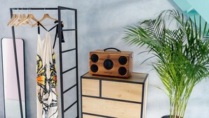 Quarto com armário de madeira, rádio, cabideiro e planta em vaso.