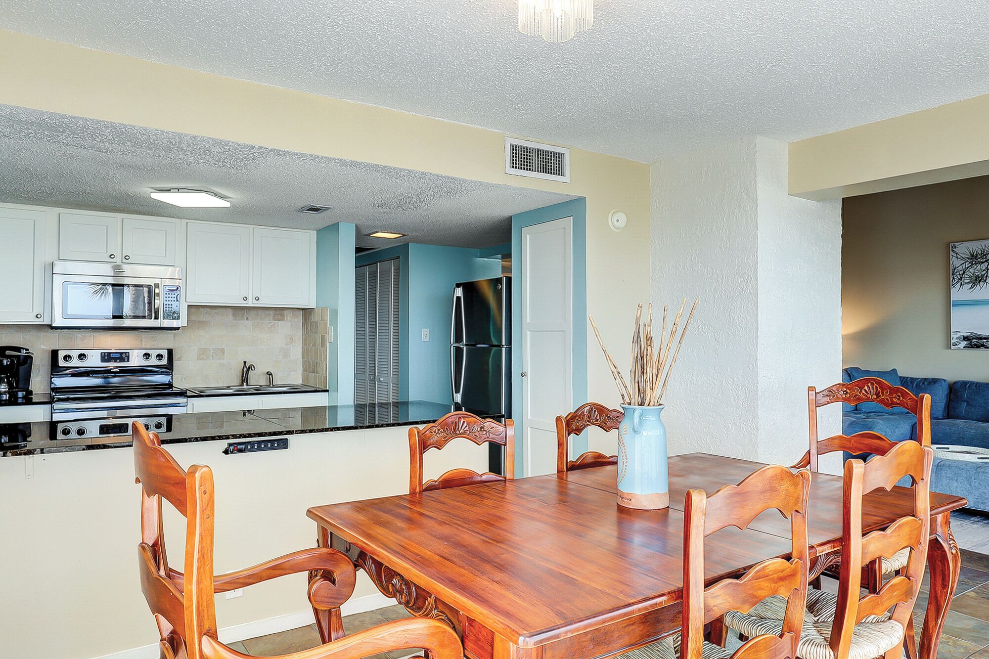 A compact kitchen with a dining area, including a wooden table and chairs, a microwave, oven, and refrigerator.