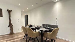 A modern dining area with a rectangular table, four chairs, and a wooden sculpture. - Elegant new building between Hamburg & Lübeck, Baltic Sea with parking lot in Reinfeld (Reinfeld)