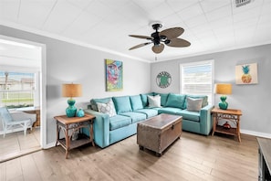 A living room with a teal sofa, wooden coffee table, and a ceiling fan.