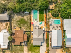 An aerial view of a residential area with multiple houses, a swimming pool, and a tennis court.