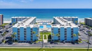 A hotel with a rooftop pool, parking lot, and ocean view.