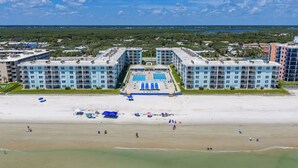 A beachfront hotel with multiple balconies, a swimming pool, and a beach area.