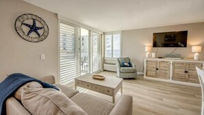 A living room with a sofa, coffee table, TV, and a decorative wall piece.