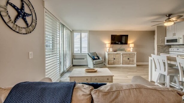 A spacious living area with a sofa, a coffee table, and a television in the background.