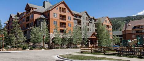 A multi-story hotel with a central courtyard, outdoor seating, and a playground.