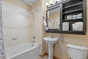 A bathroom with a bathtub, a sink, a toilet, and a mirror above the sink.