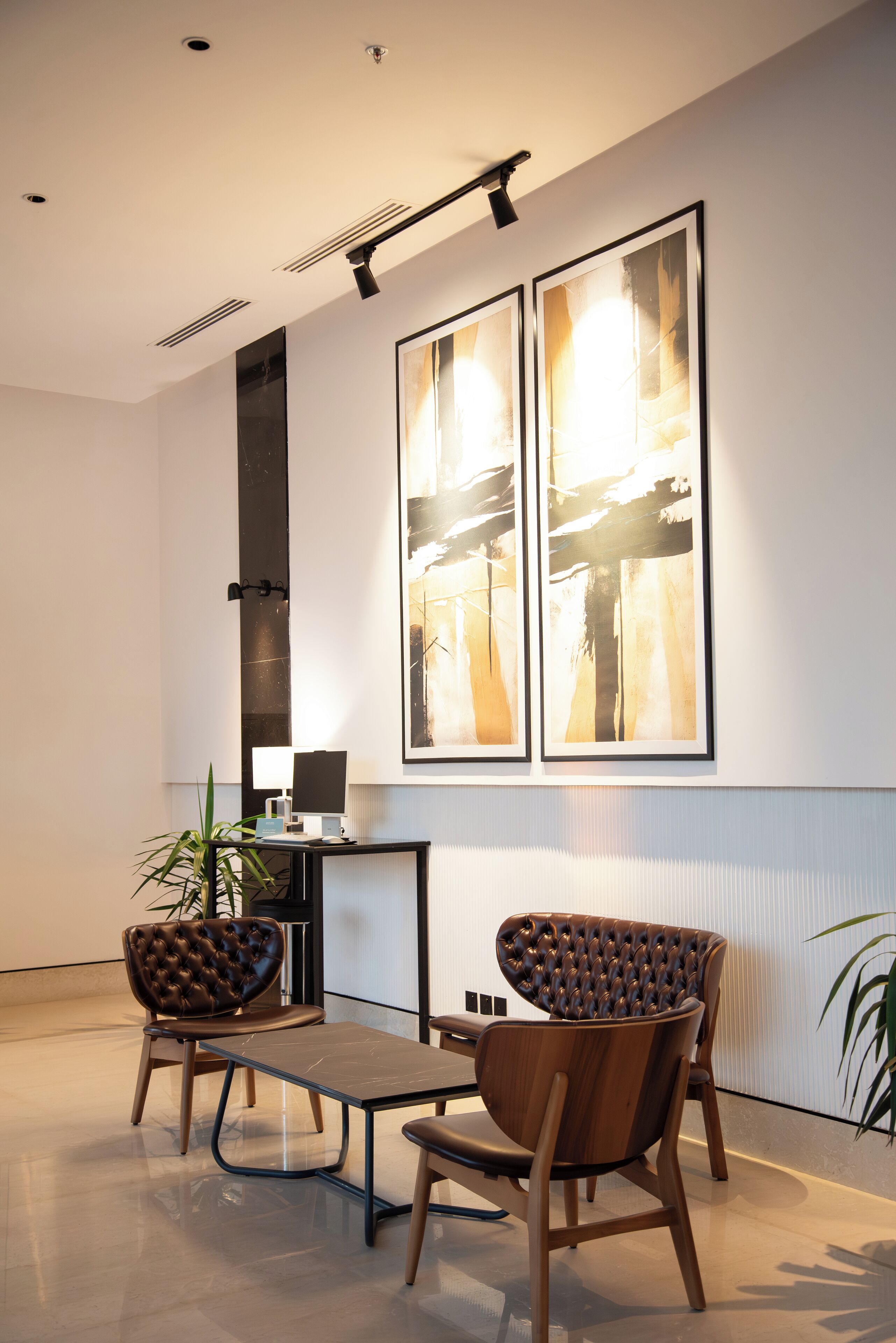 A modern interior with two leather chairs, a small table, and abstract artwork on the wall.
