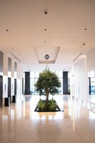 A spacious, modern lobby with a central planter with greenery, recessed lighting, and a clean, reflective floor.