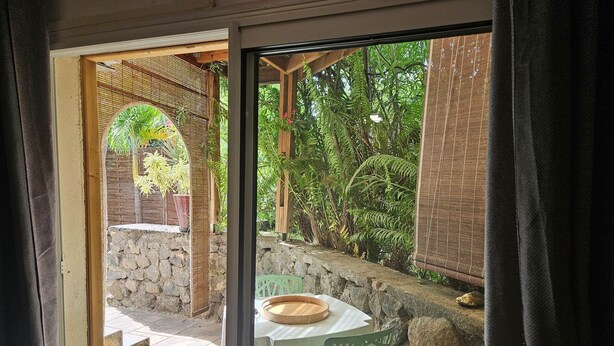 Un patio con mesa y sillas, un muro de piedra y vistas de abundante vegetación.