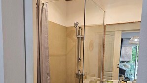 Un baño moderno con ducha de vidrio, un lavamanos blanco y un perchero para toallas.