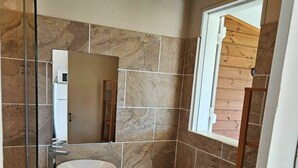 Une salle de bain avec un meuble-lavabo en bois, un lavabo blanc, des toilettes et un miroir.