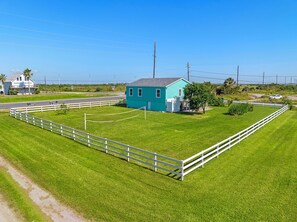 A turquoise house with a fenced yard and a road in the background. - Colva Tides | Pet Friendly + Steps to Beach! (Galveston)