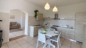 A modern kitchen with white cabinets, a dining table with chairs, and pendant lighting.