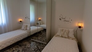A bedroom with two single beds, a large mirror, and wall decorations.