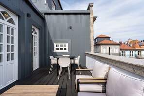 Un terrazzo con tavolo e sedie, un divano e vista sugli edifici sullo sfondo.