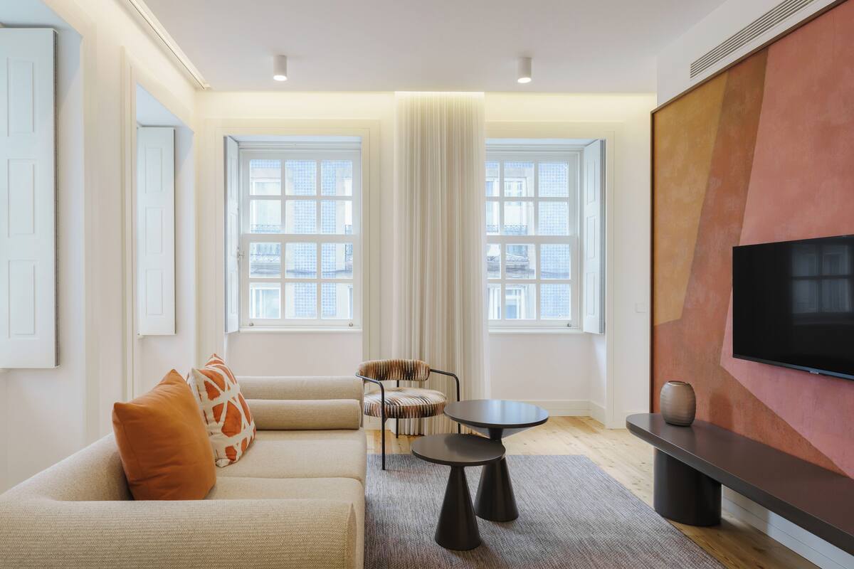A modern living room with a sofa, a chair, a small table, and a TV mounted on the wall.