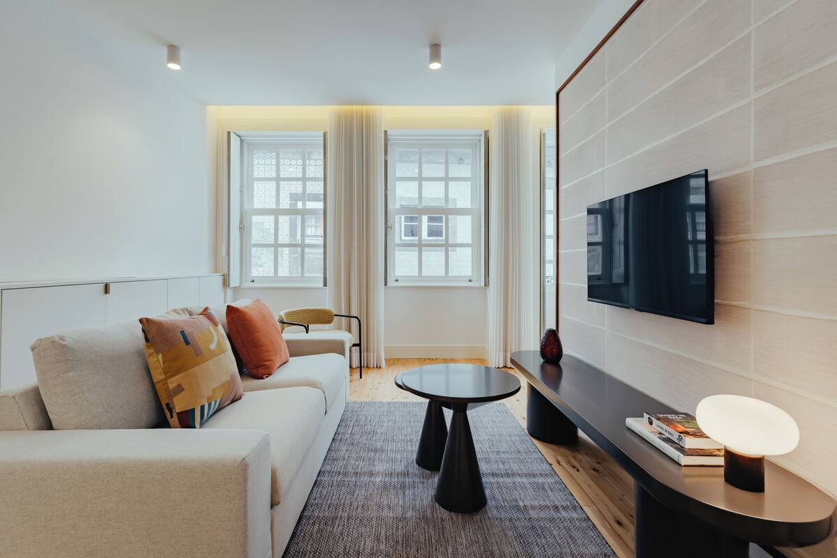 A modern living room with a sofa, a coffee table, and a flat-screen TV mounted on the wall.