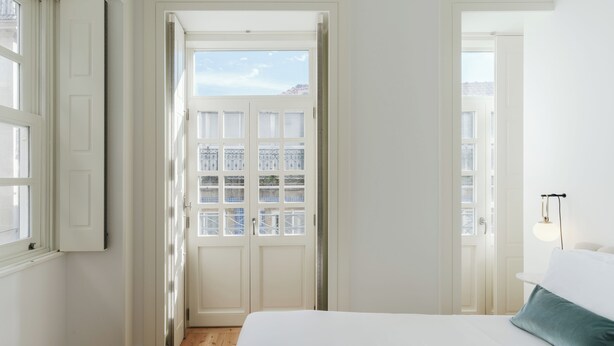 Et soveværelse med en stor seng, et vindue og en dør, der fører ud til en balkon.