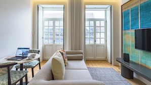 En moderne stue med sofa, sofabord, en bærbar computer og et fjernsyn.