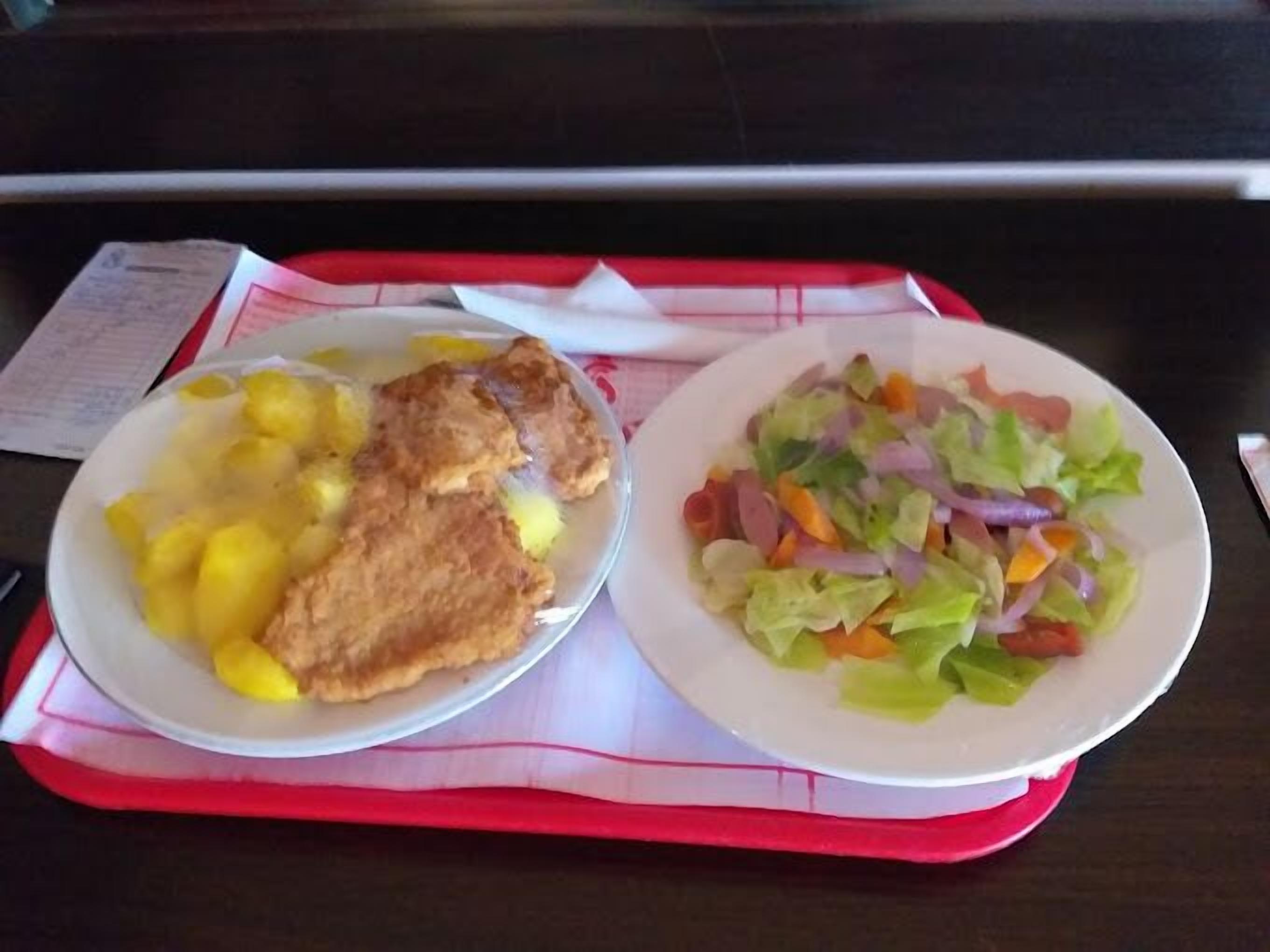Two plates of food on a tray with a menu in the background.