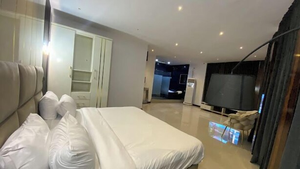 A modern hotel room with a large bed, a TV, and a wardrobe. - Dankani Guest Palace Hotel (Sokoto)