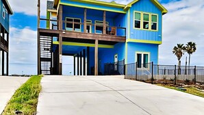 A two-story house with a balcony, a garage, and a fenced yard. - Heron House | Pet-friendly with Private Pool (Rockport)
