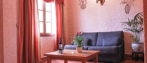 A living room with a sofa, a coffee table, and a potted plant.