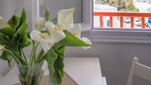 A white table with a vase of white flowers on a beige placemat. - Arodou Studio Mykonos (Mykonos)