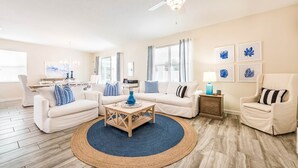 A spacious living room with a wooden coffee table, two sofas, a chair, and a TV. - South-Facing Pool & Spa • Game Room • Conservation View • Near Disney (Four Corners)