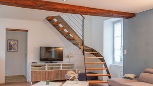 Ein modernes Wohnzimmer mit einer Holztreppe, einem Flachbildfernseher und einem Sofa.