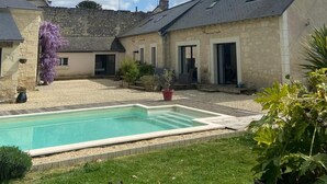 Ein Innenhof mit Pool, Steingebäuden und einer Rasenfläche.
