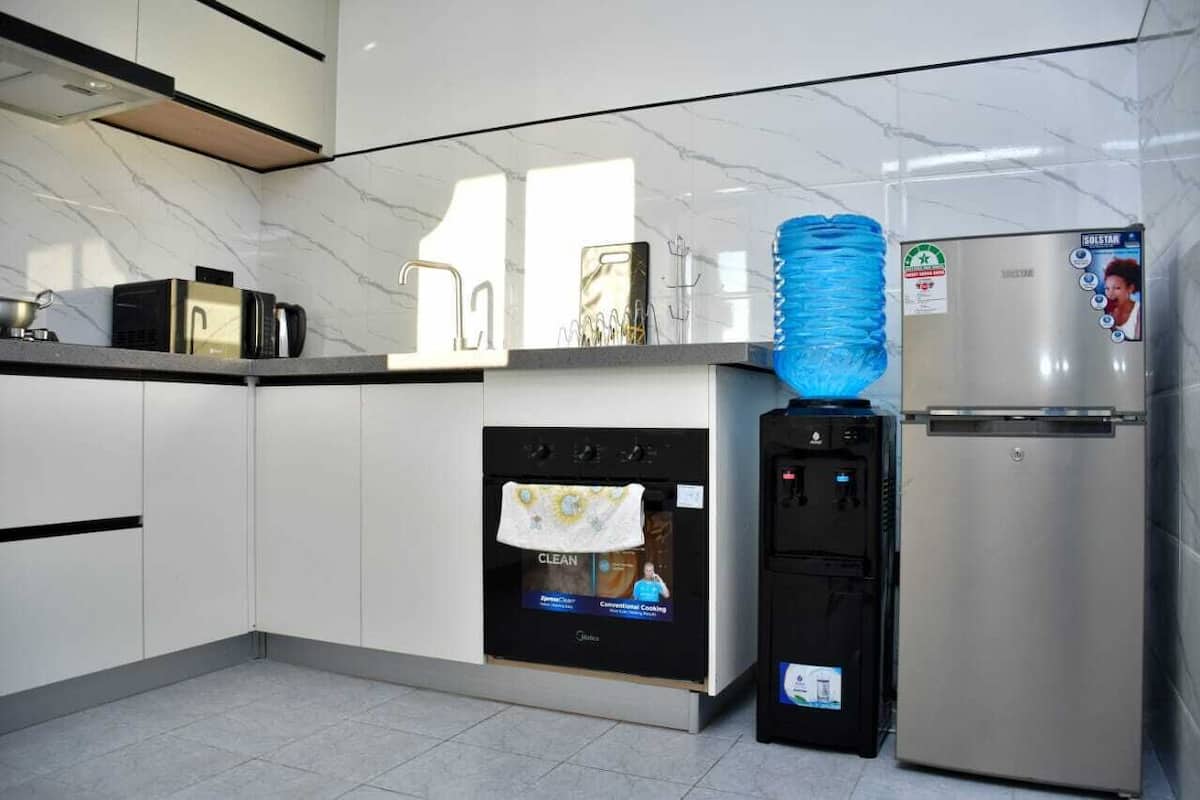Une cuisine moderne équipée d’un four encastré, d’un réfrigérateur et d’un distributeur d’eau.