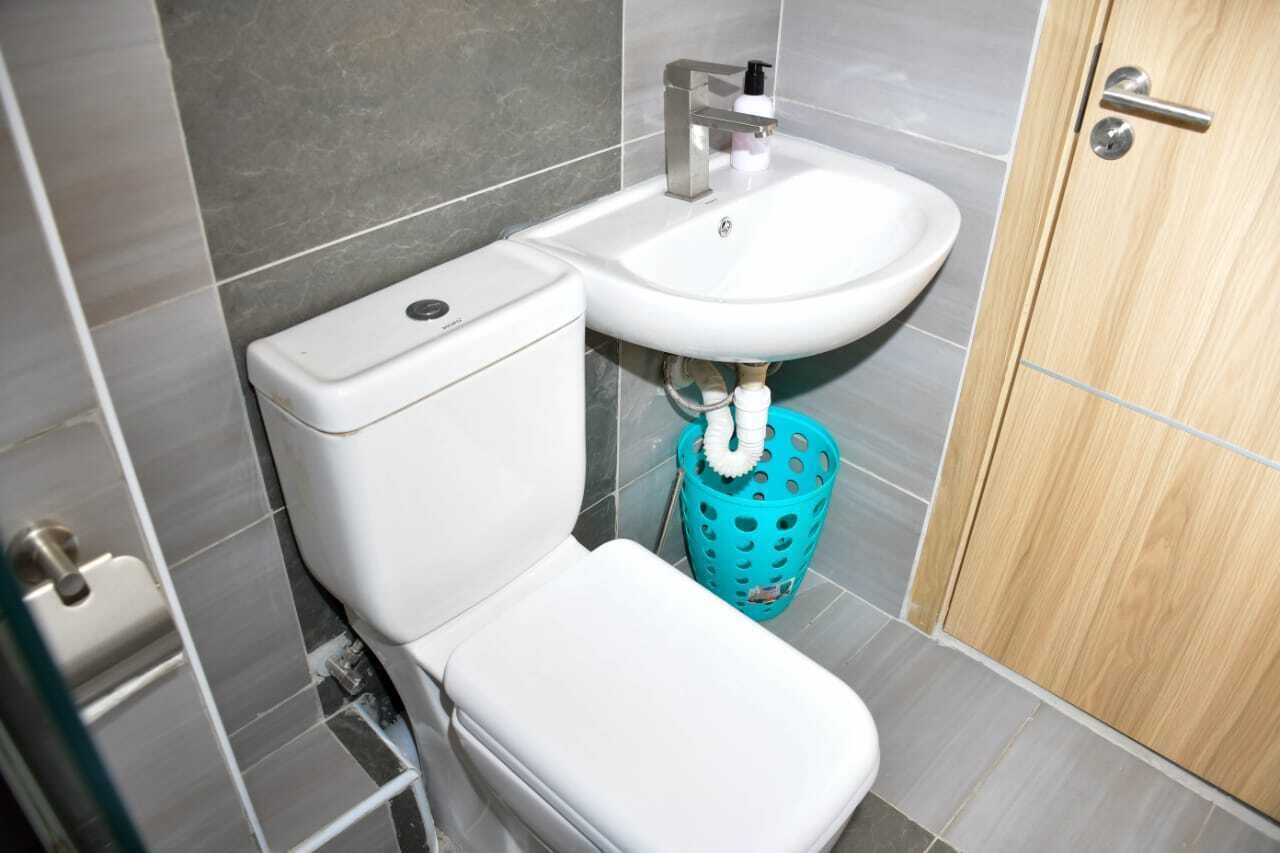 A bathroom with a toilet, sink, and a blue laundry basket.