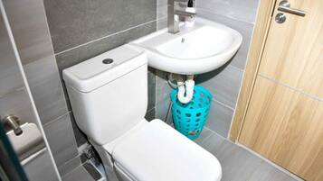 A bathroom with a toilet, sink, and a blue laundry basket.